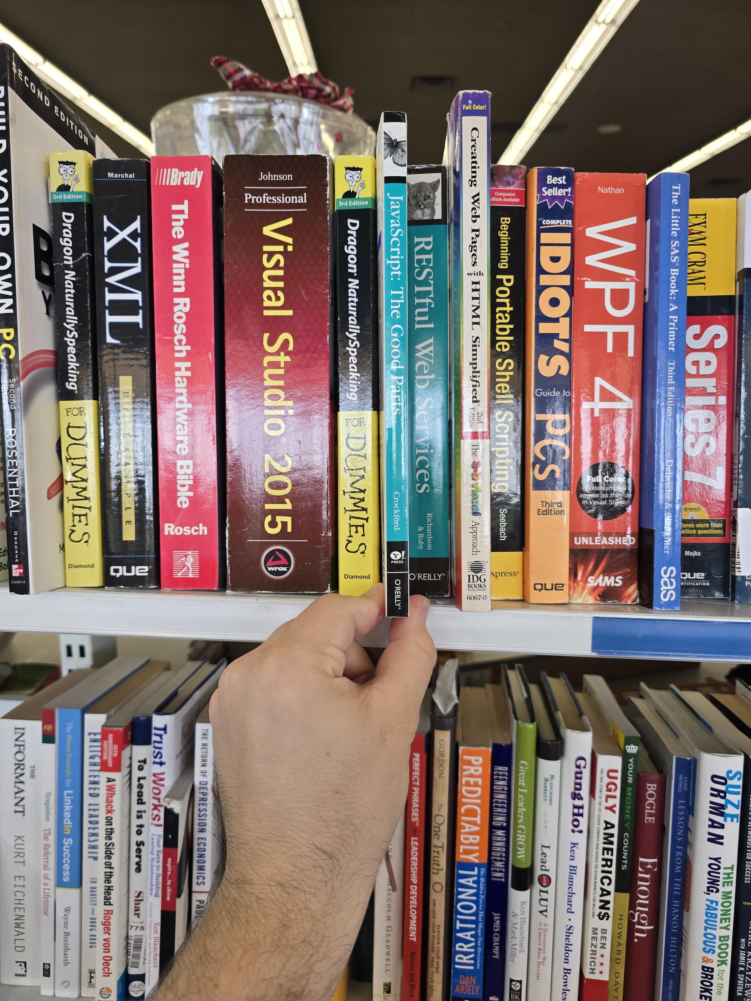 A copy of o'reily's javascript: the good parts held in front of a shelf of other thicker programming books